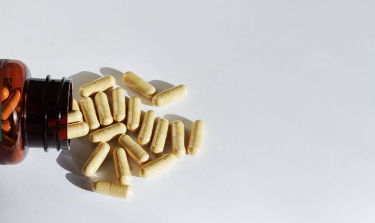 A bottle of pills and supplements on it's side with capsules spilling out